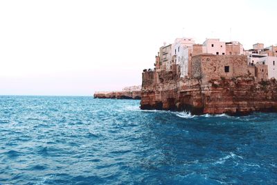 Buildings in sea against clear sky