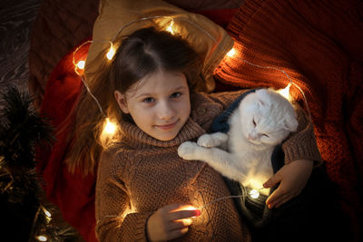 Girl child sleeps in an embrace with a cat blanket and a garland, a cozy childhood and home 