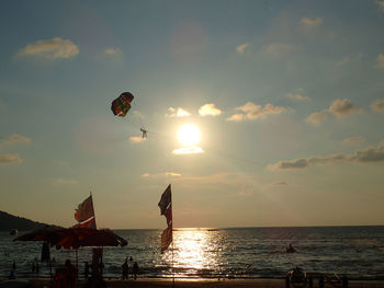 People on beach against sky during sunset