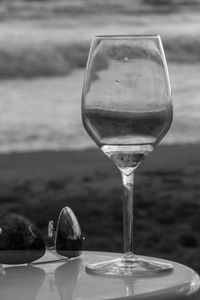 Close-up of wineglass on table against sea