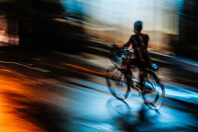 Blurred motion of man riding bicycle on road