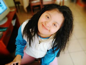 High angle portrait of smiling girl sitting at home