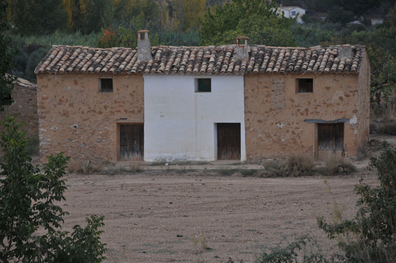 EXTERIOR OF OLD HOUSE ON FIELD AGAINST BUILDINGS