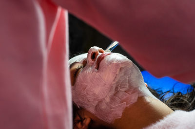 Midsection of beautician applying cream on girl face