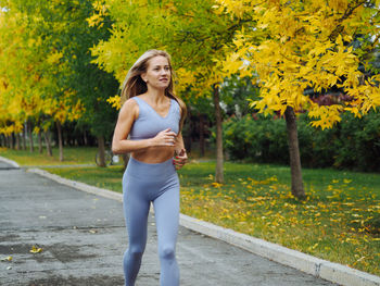 Portrait of smiling young woman standing by plants