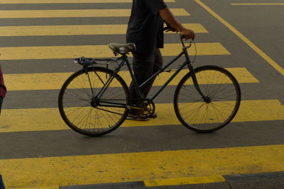 Low section of man with bicycle walking on road