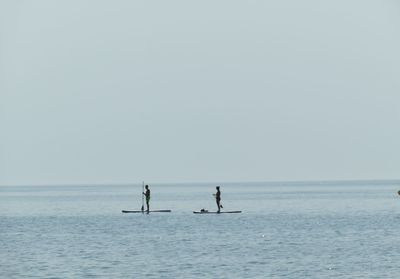 Men in sea against clear sky