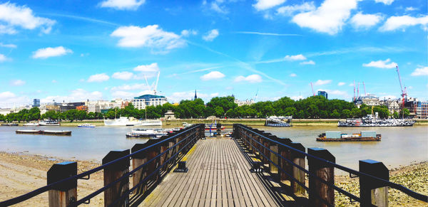 Pier over river in city against sky