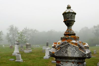 Statue at cemetery against sky