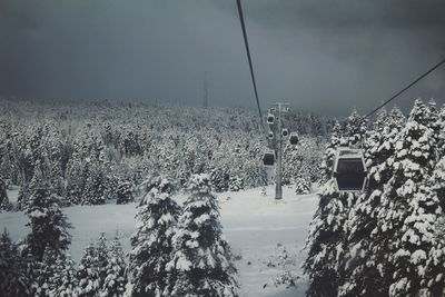 Overhead cable car over snow covered mountains against sky