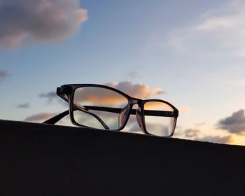 Close-up of sunglasses on table against sky during sunset