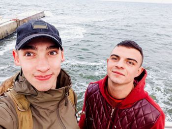 Portrait of male friends standing against sea