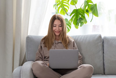 Smiling woman using laptop while sitting at home