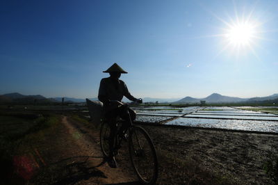 Man riding bicycle on water against sky