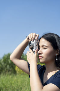 Midsection of woman photographing against clear sky