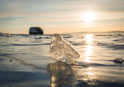 Close-up of ice on beach against sky during sunset