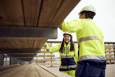 Smiling female worker examining planks with colleague at industry