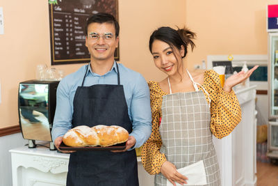 Portrait of smiling couple holding croissant