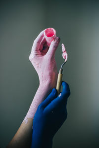 Close-up of hand holding pink petals against blue background