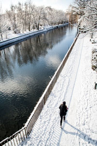 High angle view of woman jogging by canal at frozen park