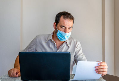 Frustrated man wearing flu mask sitting at office