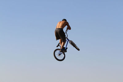 Low angle view of man riding motorcycle against clear sky