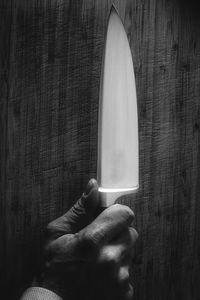 Cropped image of hand holding knife on table