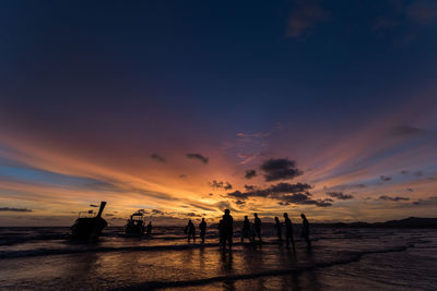 Silhouette people on beach against sky during sunset