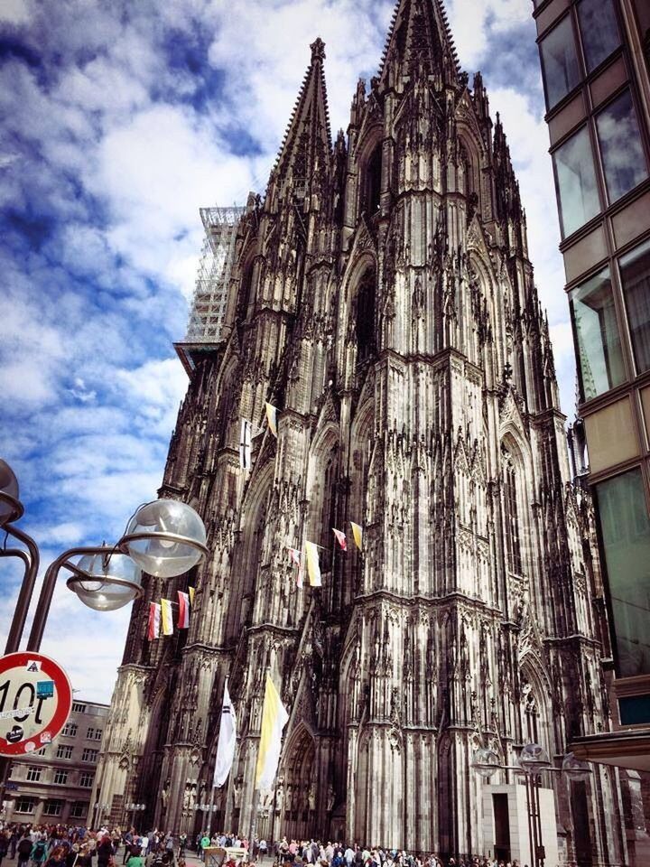 building exterior, architecture, built structure, sky, city, travel destinations, famous place, low angle view, large group of people, religion, tourism, cathedral, cloud - sky, place of worship, travel, capital cities, church, city life