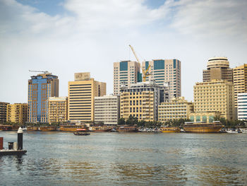 River by modern buildings against sky in city