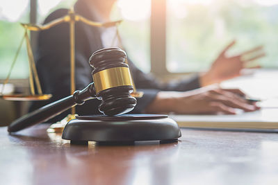 Close-up of gavel on table with female lawyer in background at office