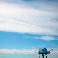 Low angle view of blue fishing hut against blue sky