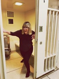 Portrait of woman standing against door at home