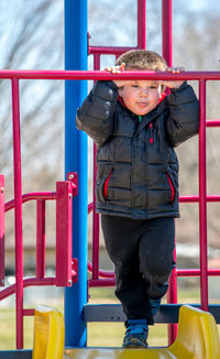 Bored little boy surveys the playground from the top of the playground slide 