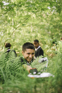 Smiling boy picking up plastic from plant