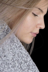 Close-up of young woman with blond hair against black background