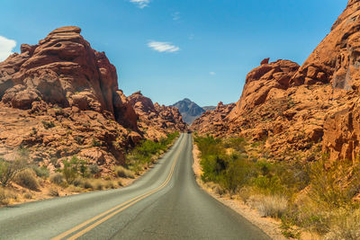 Road leading towards mountains against sky