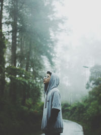 Side view of man standing in forest