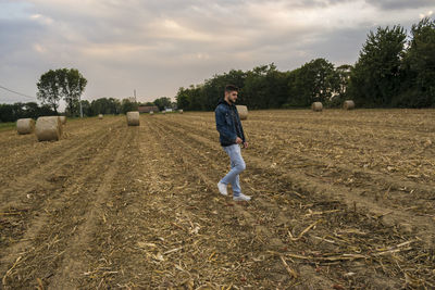 People on dirt road against cloudy sky