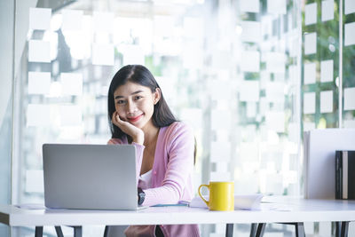 Portrait of a smiling young woman using phone