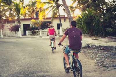 Man and woman riding bicycles in tropical rural town