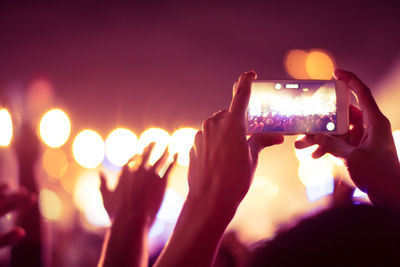 Low angle view of hand holding smart phone at music concert