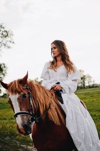 Young woman riding horse on field