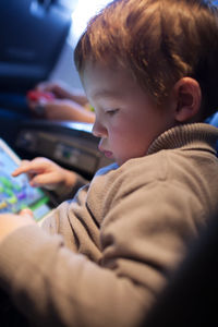 Cute boy using digital tablet while sitting in airplane