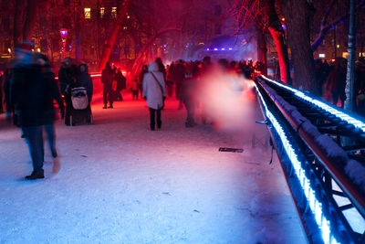 Group of people walking on snow covered city at night