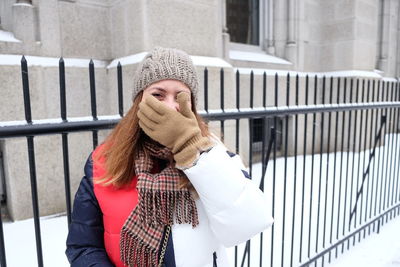 Portrait of young woman standing against building