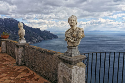 Statue by sea against sky