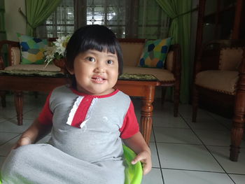 Portrait of cute girl sitting on floor at home