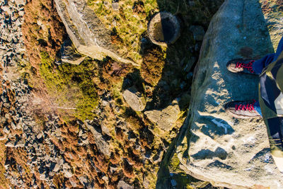 Low section of woman standing on rock by water