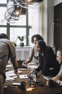 Businesswomen discussing plan with male colleagues at conference table in creative office